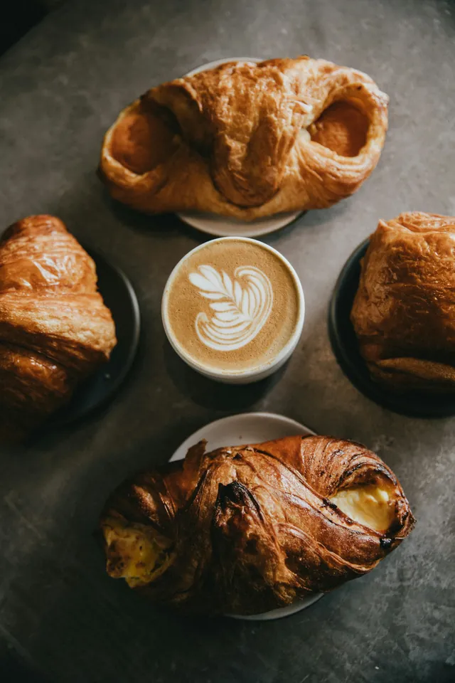 Secangkir kopi susu dikelilingi empat pastry