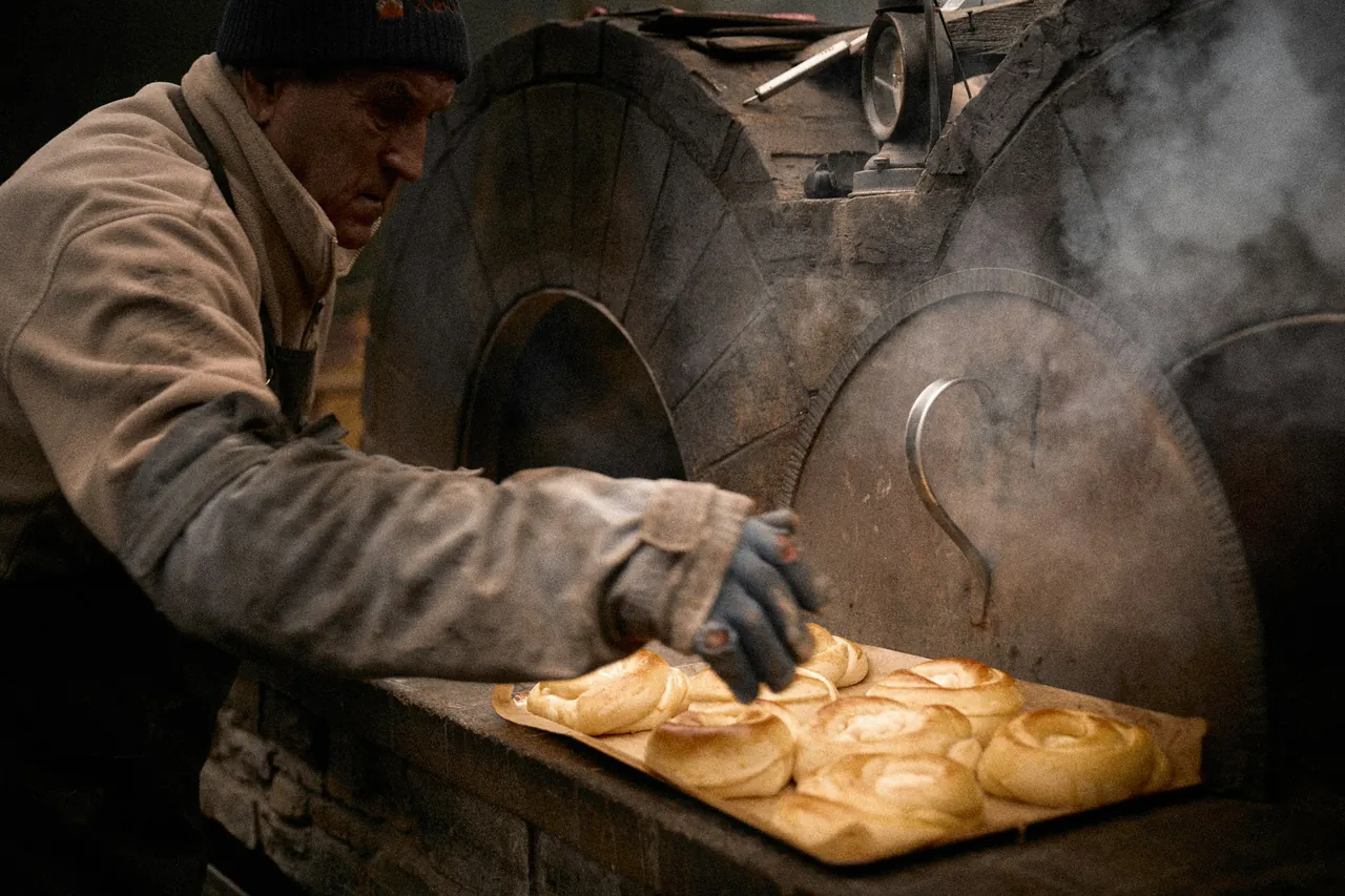 Pembuat roti memasukkan loyang pastry ke oven batu